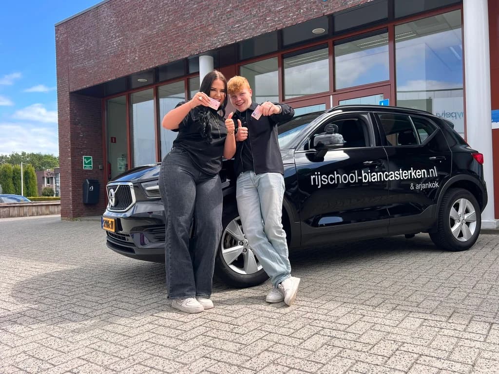 Vooraanzicht van de zwarte Volvo lesauto met het blauwe Rijschool Bianca Sterken dakbord.